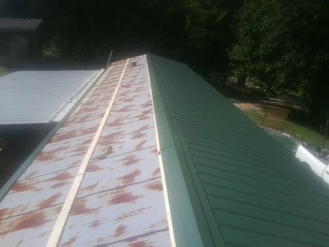 Old rusted panels beside newly installed green metal roofing — Wind Damage Roof Repair by Roofing Brothers in King William