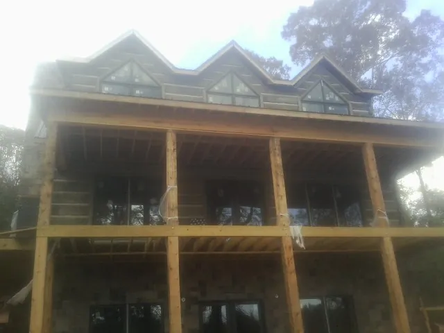 Dormers and porch framing on a large log home under construction — Roof Coating work by our crew in King William