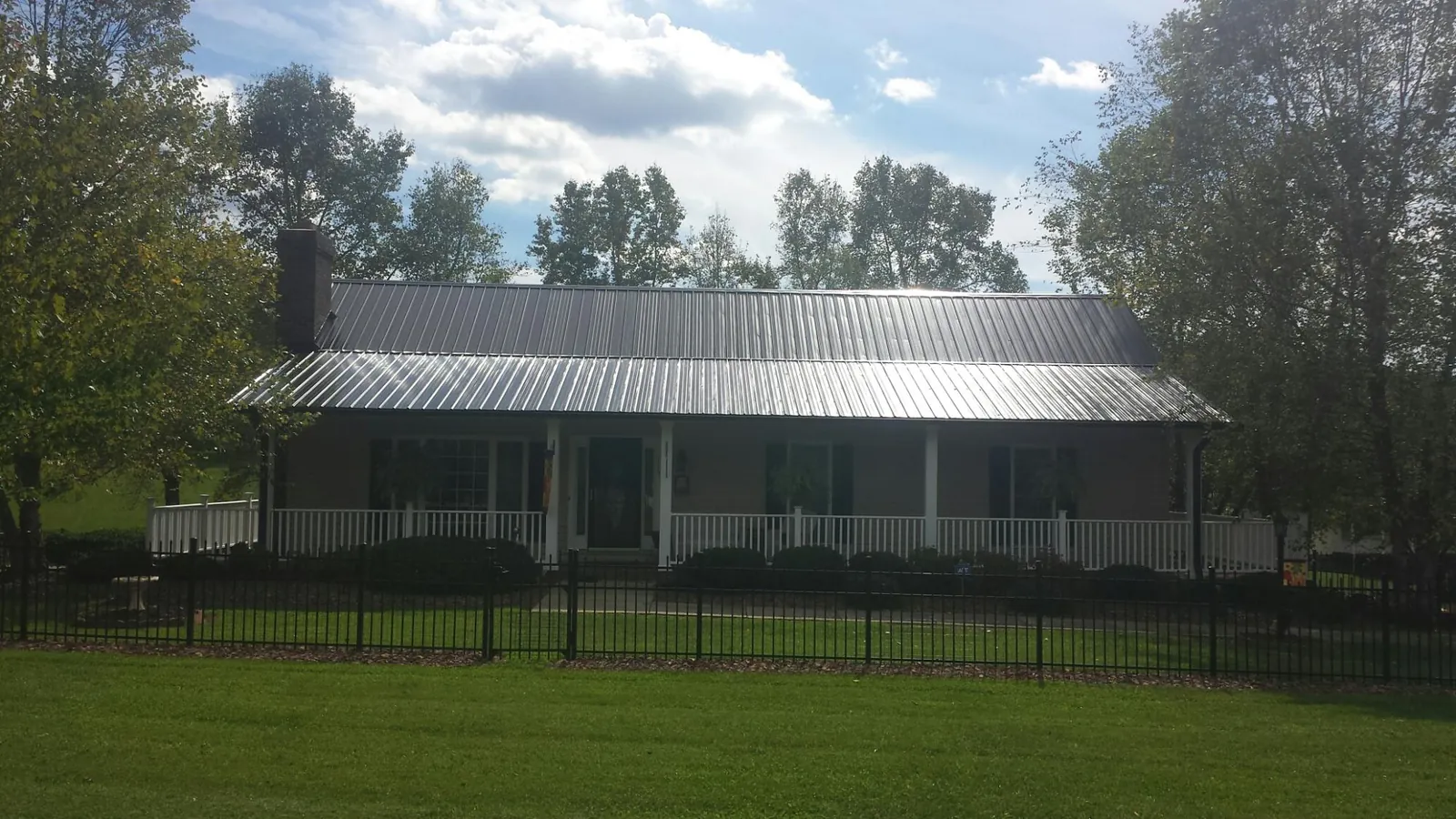 Gray metal roof on a brick ranch with a full width front porch — Gutter Guard Installation work by our crew in King William