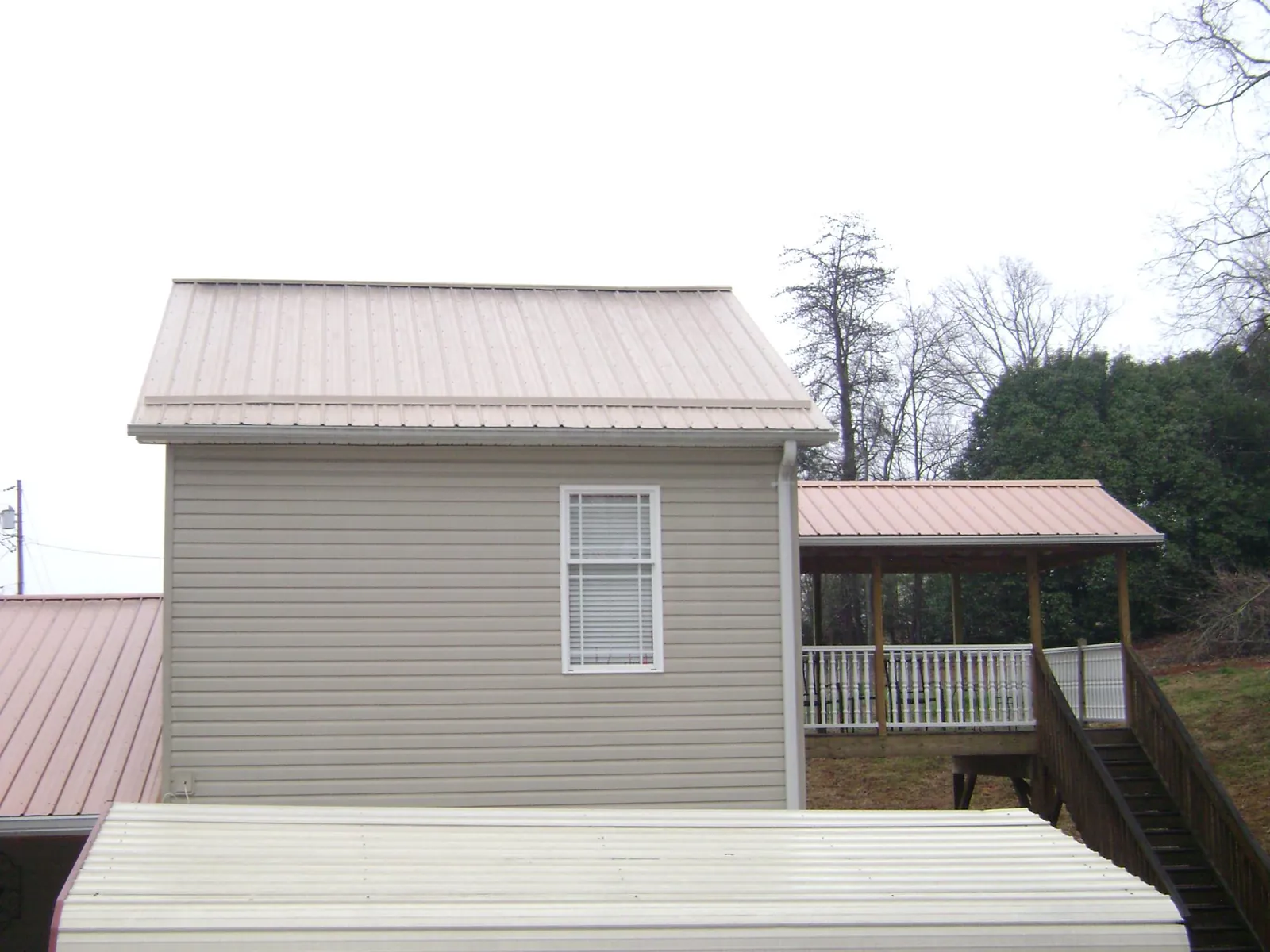 Tan metal roofs on a two story addition and attached porch, from a Roof Replacement job in King William